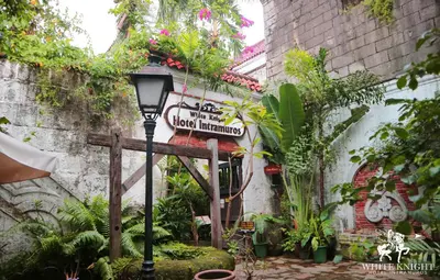a street sign in front of a building with plants at White Knight Hotel Intramuros in Manila