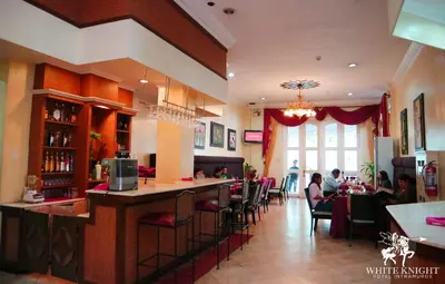 a restaurant with a bar and people sitting at tables at White Knight Hotel Intramuros in Manila
