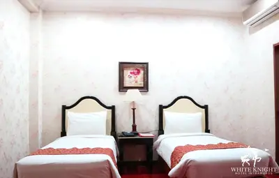 two beds in a room with white walls at White Knight Hotel Intramuros in Manila