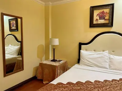 a hotel room with a bed and a mirror at White Knight Hotel Intramuros in Manila