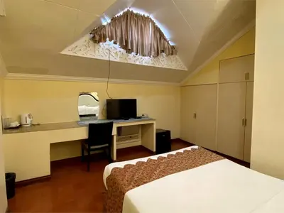 a bedroom with a bed and a desk with a computer at White Knight Hotel Intramuros in Manila