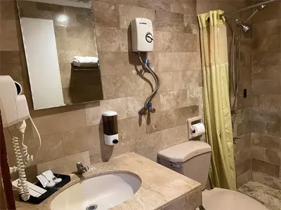 a bathroom with a sink and a toilet and a mirror at White Knight Hotel Intramuros in Manila
