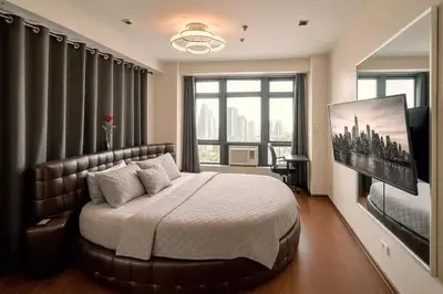 a bedroom with a large bed and a flat screen tv at 2-story Penthouse with 5 Balconies in Manila