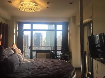 a bedroom with a bed and a large window at 2-story Penthouse with 5 Balconies in Manila