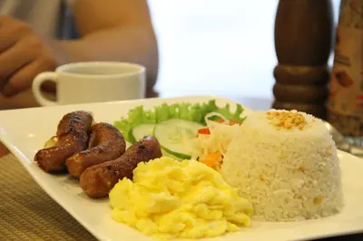 a plate of food with sausage eggs rice and vegetables at Hotel Marciano in Calamba