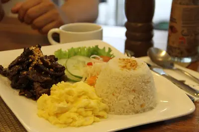 a plate of food with rice and vegetables on a table at Hotel Marciano in Calamba
