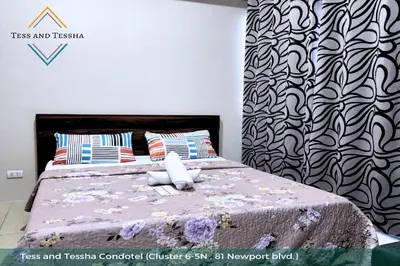 a bedroom with a bed with a black and white patterned wall at Tess and Tessha Condotel near T3 Airport in Manila