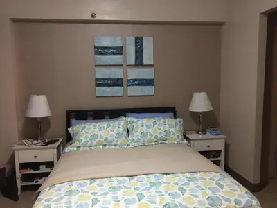 a bedroom with a bed with two nightstands and two lamps at De Luxe 7QRS in Manila