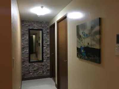 a hallway with a mirror and a painting on a wall at De Luxe 7QRS in Manila