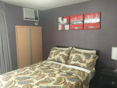 a bedroom with a bed and two posters on the wall at De Luxe 7QRS in Manila