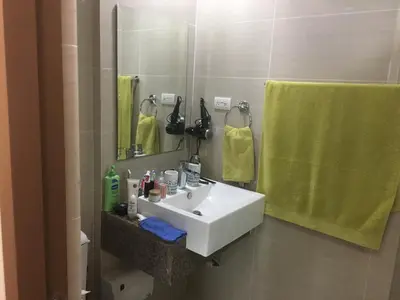 a bathroom with a white sink and a green towel at De Luxe 7QRS in Manila
