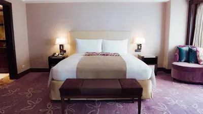 a hotel room with a large bed and a chair at Diamond Hotel Philippines in Manila