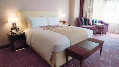 a hotel room with a large bed and a chair at Diamond Hotel Philippines in Manila