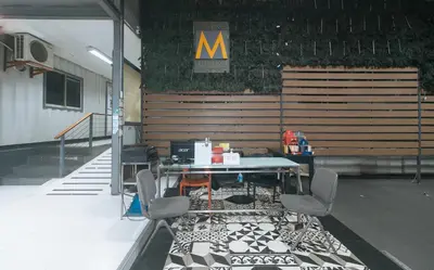 a table and chairs in a room with a m sign at Metro Deluxe Residences near World Trade Center in Manila