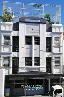 a white building with a car parked in front of it at Frank Lloyd Apartelle in Manila