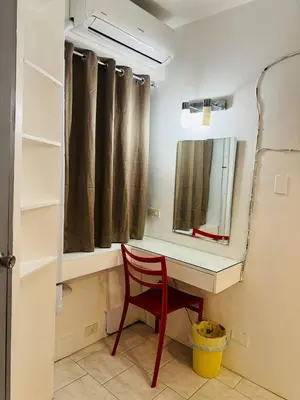 a red chair sitting in front of a desk with a mirror at Frank Lloyd Apartelle in Manila