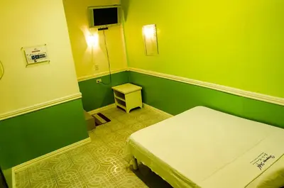 a small green room with a bed and a small table at Dreamwave Resort Pansol Laguna in Calamba