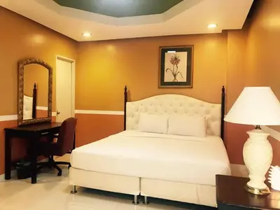 a bedroom with a white bed and a desk and a mirror at Dreamwave Resort Pansol Laguna in Calamba