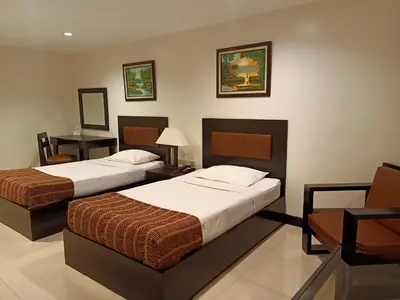 a hotel room with two beds and a table at Paragon Tower Hotel in Manila