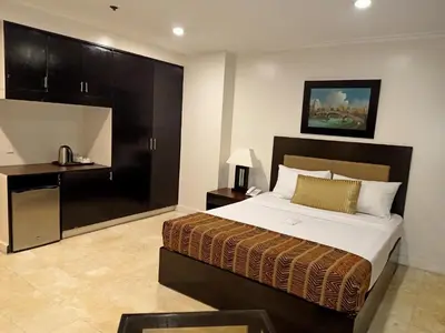 a bedroom with a large bed and a desk at Paragon Tower Hotel in Manila