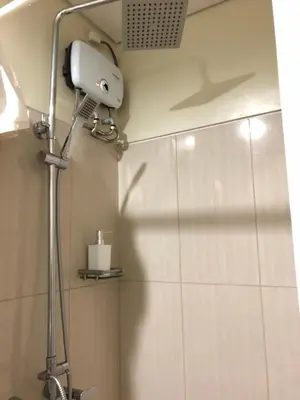 a shower head in a bathroom with a mirror at RLR Condo at Shell Residences in Manila