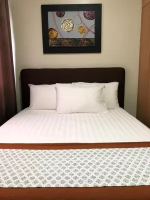 a bed with white sheets and a picture on the wall at RLR Condo at Shell Residences in Manila