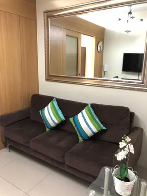 a brown couch in a living room with a mirror at RLR Condo at Shell Residences in Manila