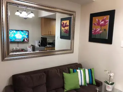 a living room with a brown couch and a mirror at RLR Condo at Shell Residences in Manila
