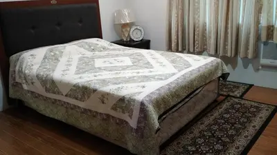 a bed with a quilt on it in a bedroom at Burgundy McKinley Place in Manila