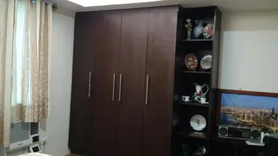a large wooden cabinet in a living room at Burgundy McKinley Place in Manila