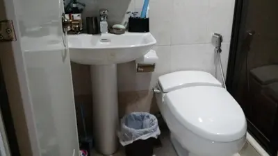 a bathroom with a white toilet and a sink at Burgundy McKinley Place in Manila