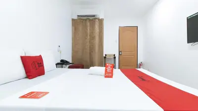 a bedroom with a white bed with a red blanket at RedDoorz at San Antonio Makati in Manila