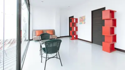 a room with chairs and a table and a shelf at RedDoorz at San Antonio Makati in Manila