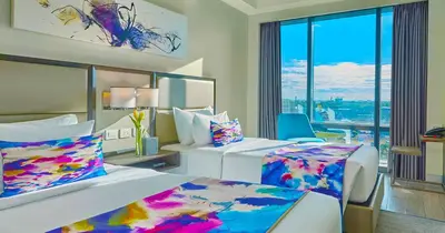a hotel room with two beds and a large window at Savoy Hotel Manila near Airport NAIA Terminal 3 MNL in Manila