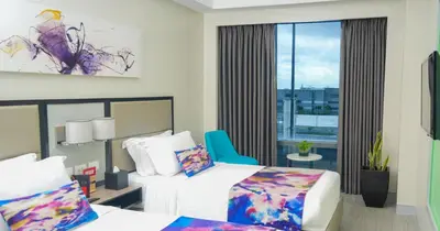 a hotel room with two beds and a blue chair at Savoy Hotel Manila near Airport NAIA Terminal 3 MNL in Manila