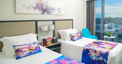 a hotel room with two beds and a chair at Savoy Hotel Manila near Airport NAIA Terminal 3 MNL in Manila