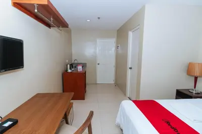 a bedroom with a bed and a desk and a tv at RedDoorz near Osmena Highway 1 in Manila