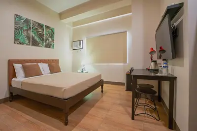 a bedroom with a bed and a desk and a television at Achievers Airport Hotel in Manila
