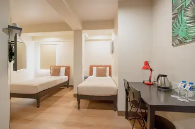 a room with two beds and a desk in it at Achievers Airport Hotel in Manila