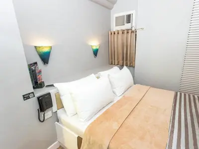 a small bedroom with a bed with white pillows at Urban Travellers Hotel in Manila