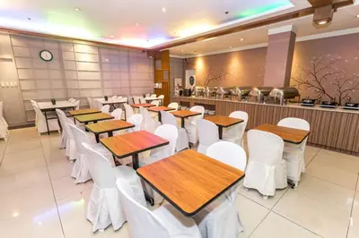 a dining room with wooden tables and white chairs at Urban Travellers Hotel in Manila