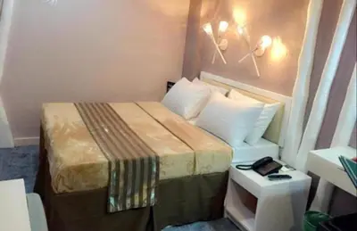 a hotel room with a bed and a side table at Urban Travellers Hotel in Manila