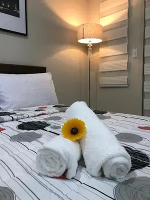 a towel with a flower on top of a bed at One Palm Tree Apartments in Manila