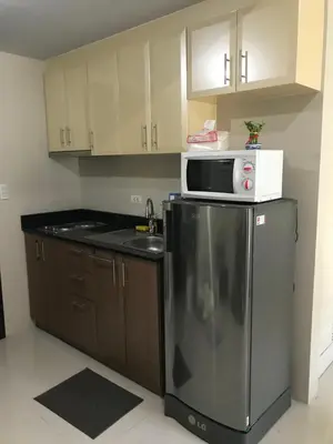 a kitchen with a microwave on top of a refrigerator at One Palm Tree Apartments in Manila