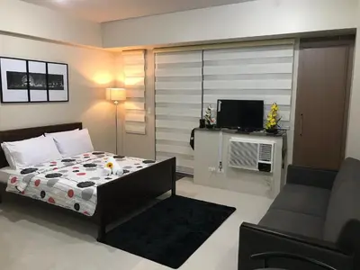 a bedroom with a bed and a couch and a television at One Palm Tree Apartments in Manila