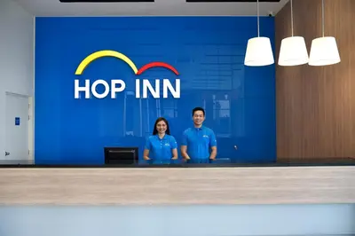 a man and woman standing in front of a hop inn sign at Hop Inn Hotel Aseana City Manila in Manila