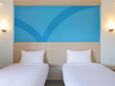 two beds in a room with a painting on the wall at Hop Inn Hotel Aseana City Manila in Manila