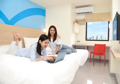 two women sitting on a bed with a laptop at Hop Inn Hotel Aseana City Manila in Manila