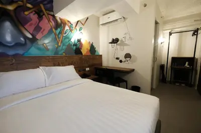 a bedroom with a white bed and a painting on the wall at U Hotels Makati in Manila