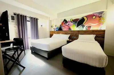 a bedroom with two beds and a desk with a computer at U Hotels Makati in Manila